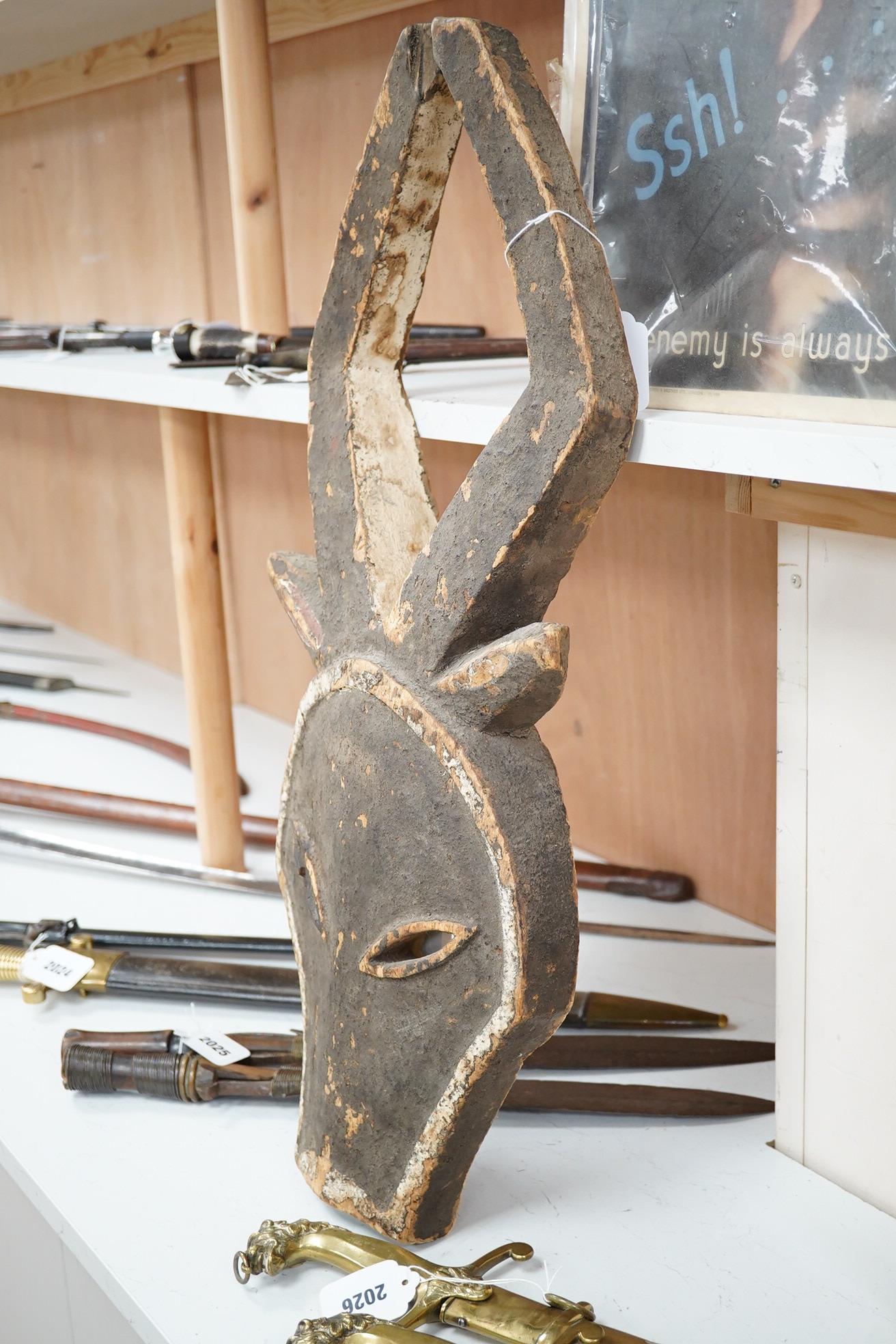 A Kwele painted wood mask in the form of an antelope’s head, 68cm high. Condition - fair, some paint loss.